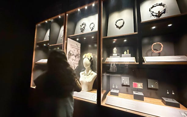 Jewelry display at Frida Kahlo Museum, La Casa Roja, with visitor observing exhibits.