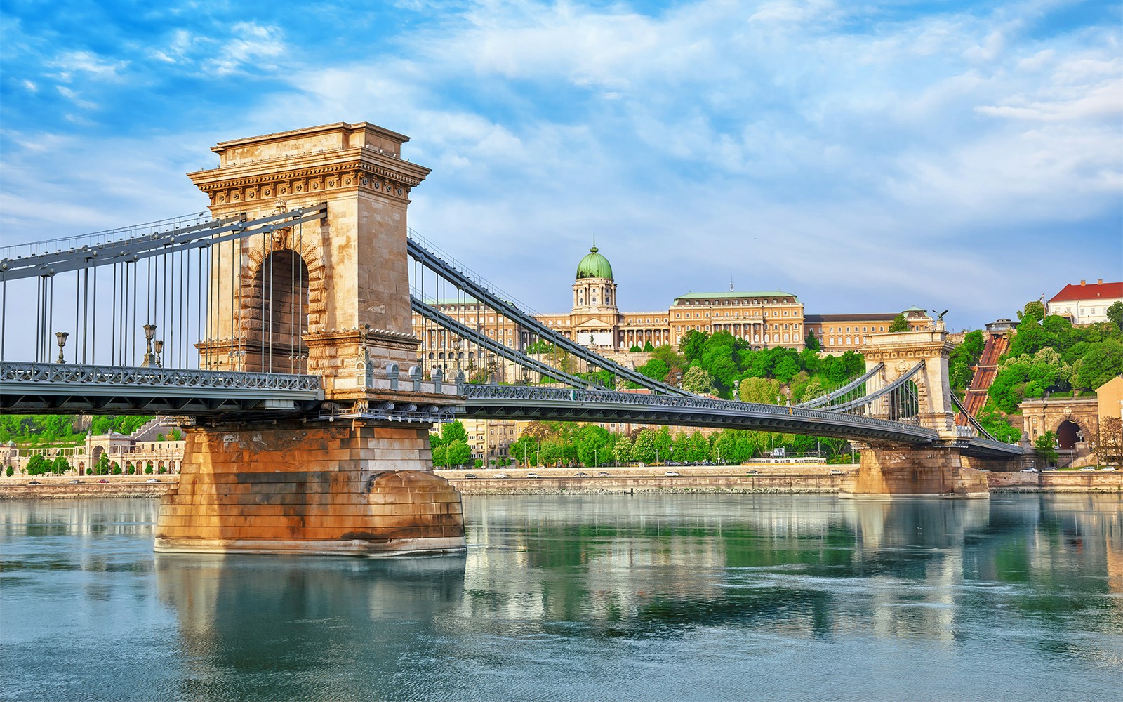 Szechenyi Chain Bridge spanning the Danube River in Budapest, Hungary, with cityscape in the background.