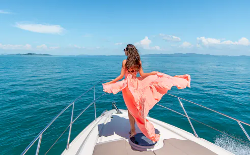 Woman on boat enjoying Baunei Coast during full-day guided tour.