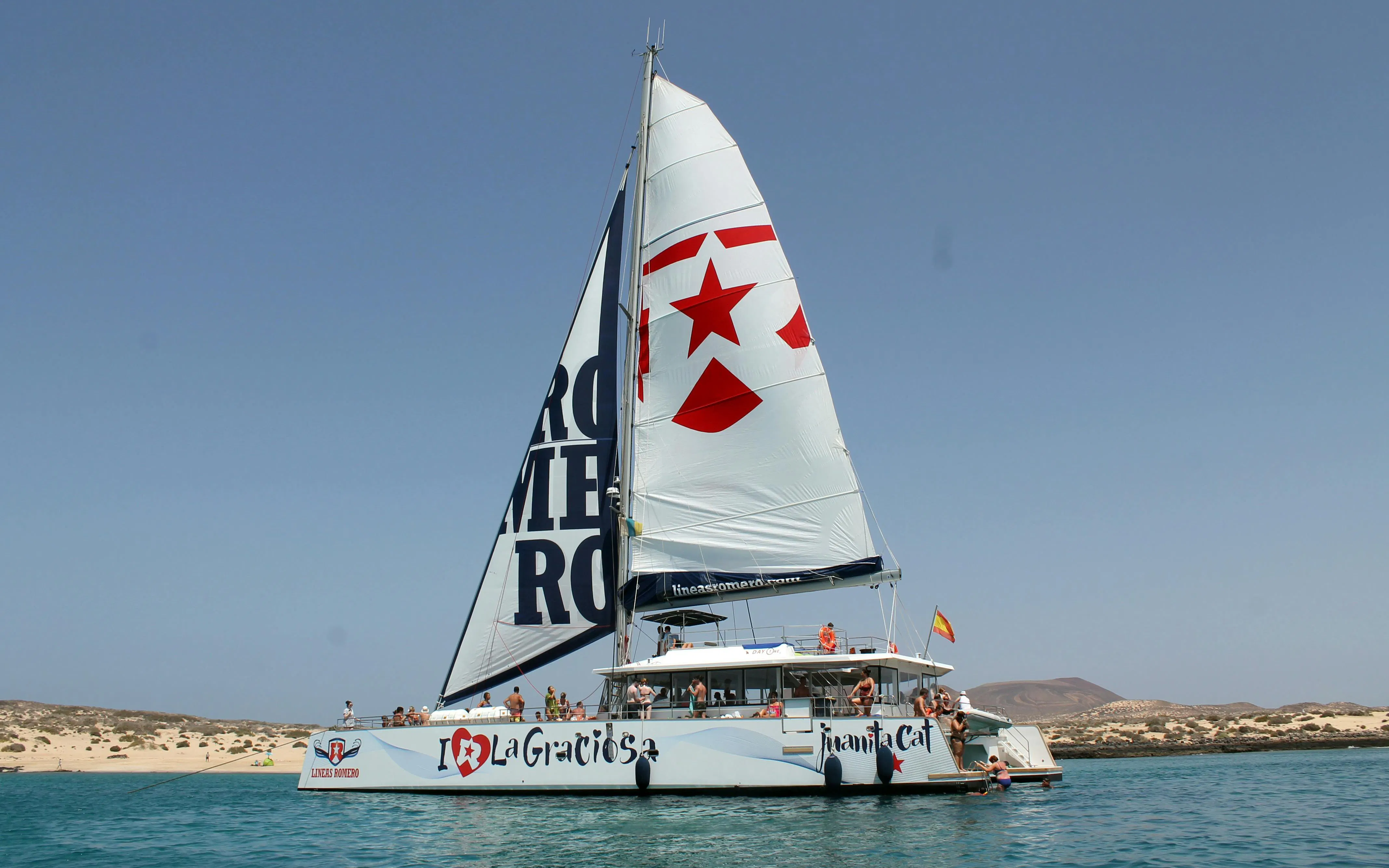 Catamaran sailing near La Graciosa Island with passengers enjoying the cruise.