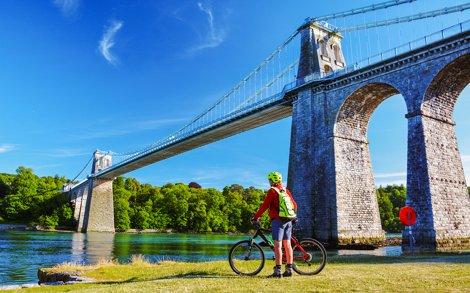 Cyclist at Menai Suspension Bridge in Anglesea, showcasing scenic views.