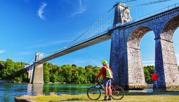 Cyclist at Menai Suspension Bridge in Anglesea, showcasing scenic views.