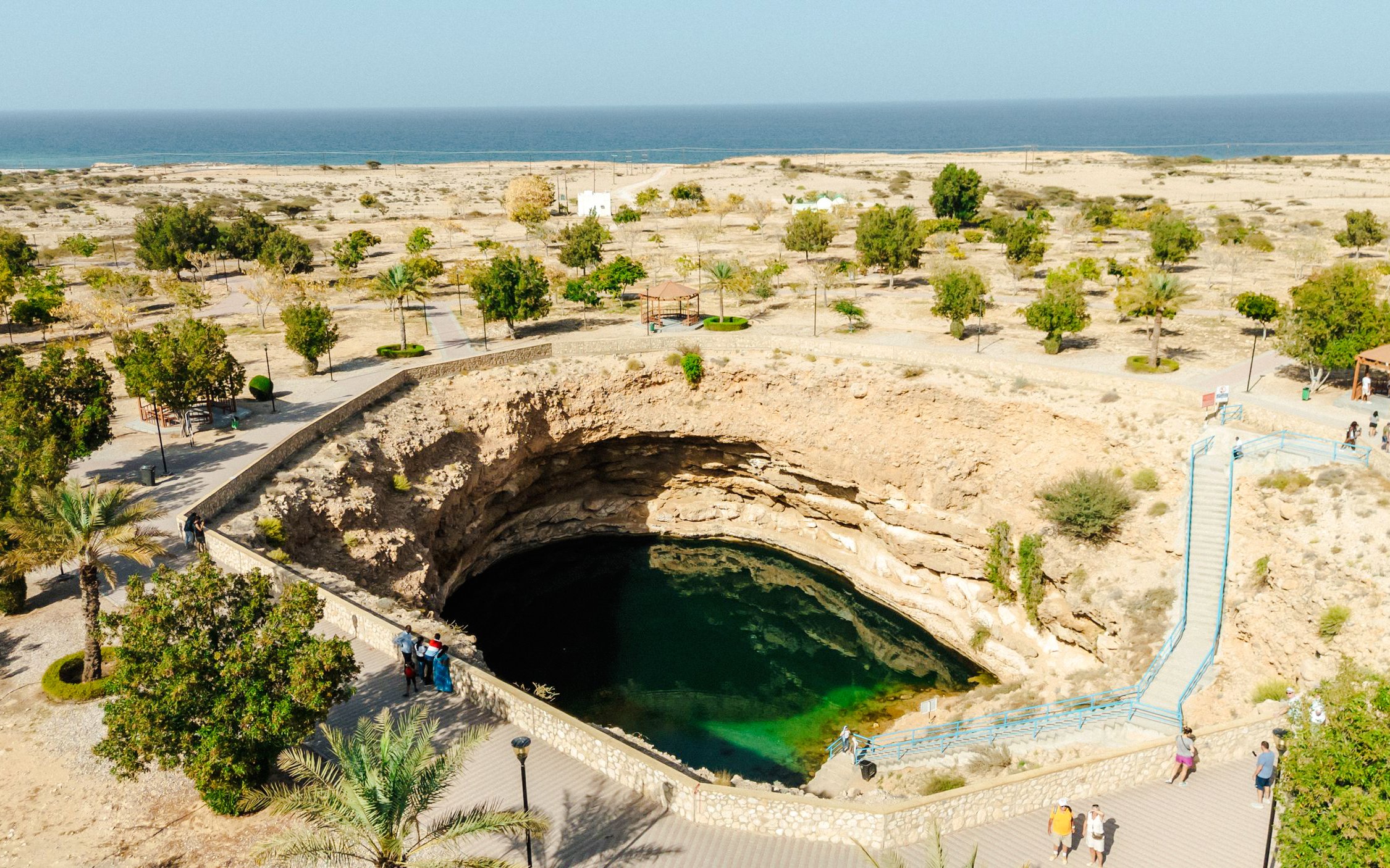 Bimmah Sinkhole in Oman with turquoise water surrounded by desert landscape.