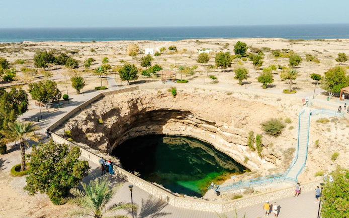Bimmah Sinkhole in Oman with turquoise water surrounded by desert landscape.