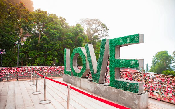 LOVE sculpture at Penang Hill with padlocks on fence, Malaysia