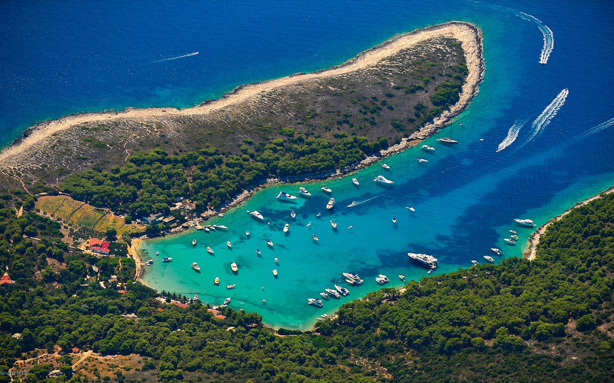 Aerial view of boats in a turquoise bay surrounded by lush greenery on a 5 Islands Hopping tour.