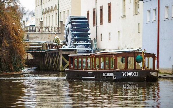 Prague sightseeing boat cruise near historical water mill.