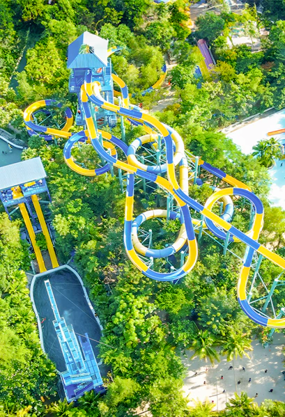 Aerial view of colorful water slides at Escape Penang theme park, surrounded by lush greenery.