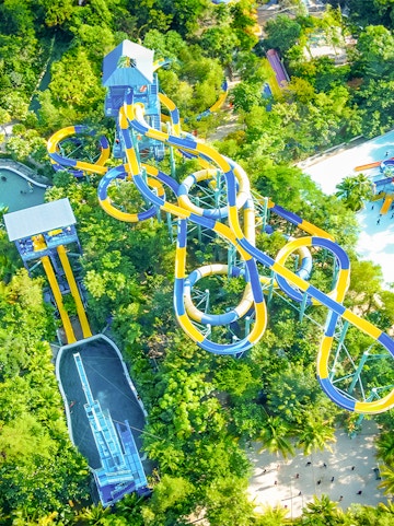 Aerial view of colorful water slides at Escape Penang theme park, surrounded by lush greenery.