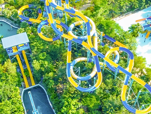 Aerial view of colorful water slides at Escape Penang theme park, surrounded by lush greenery.