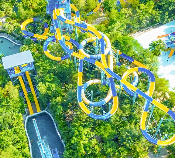 Aerial view of colorful water slides at Escape Penang theme park, surrounded by lush greenery.