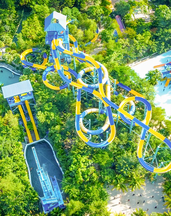 Aerial view of colorful water slides at Escape Penang theme park, surrounded by lush greenery.
