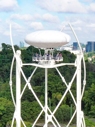 Skyhelix ride with passengers above lush greenery in Sentosa, Singapore.