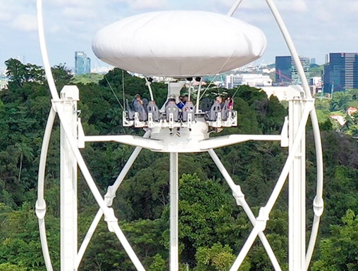 Skyhelix ride with passengers above lush greenery in Sentosa, Singapore.