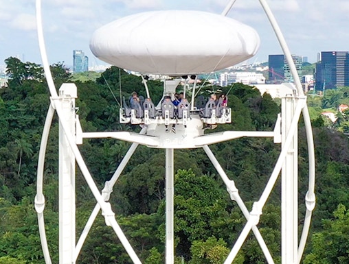 Skyhelix ride with passengers above lush greenery in Sentosa, Singapore.