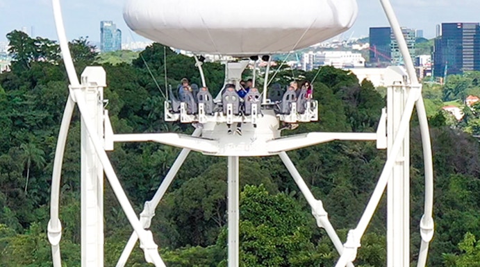 Skyhelix ride with passengers above lush greenery in Sentosa, Singapore.