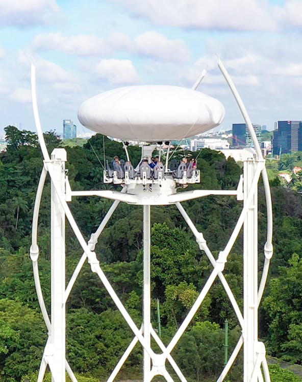Skyhelix ride with passengers above lush greenery in Sentosa, Singapore.