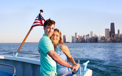 Couple enjoying Chicago River & Lake Sightseeing Cruise with city skyline in background.