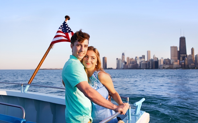 Couple enjoying Chicago River & Lake Sightseeing Cruise with city skyline in background.