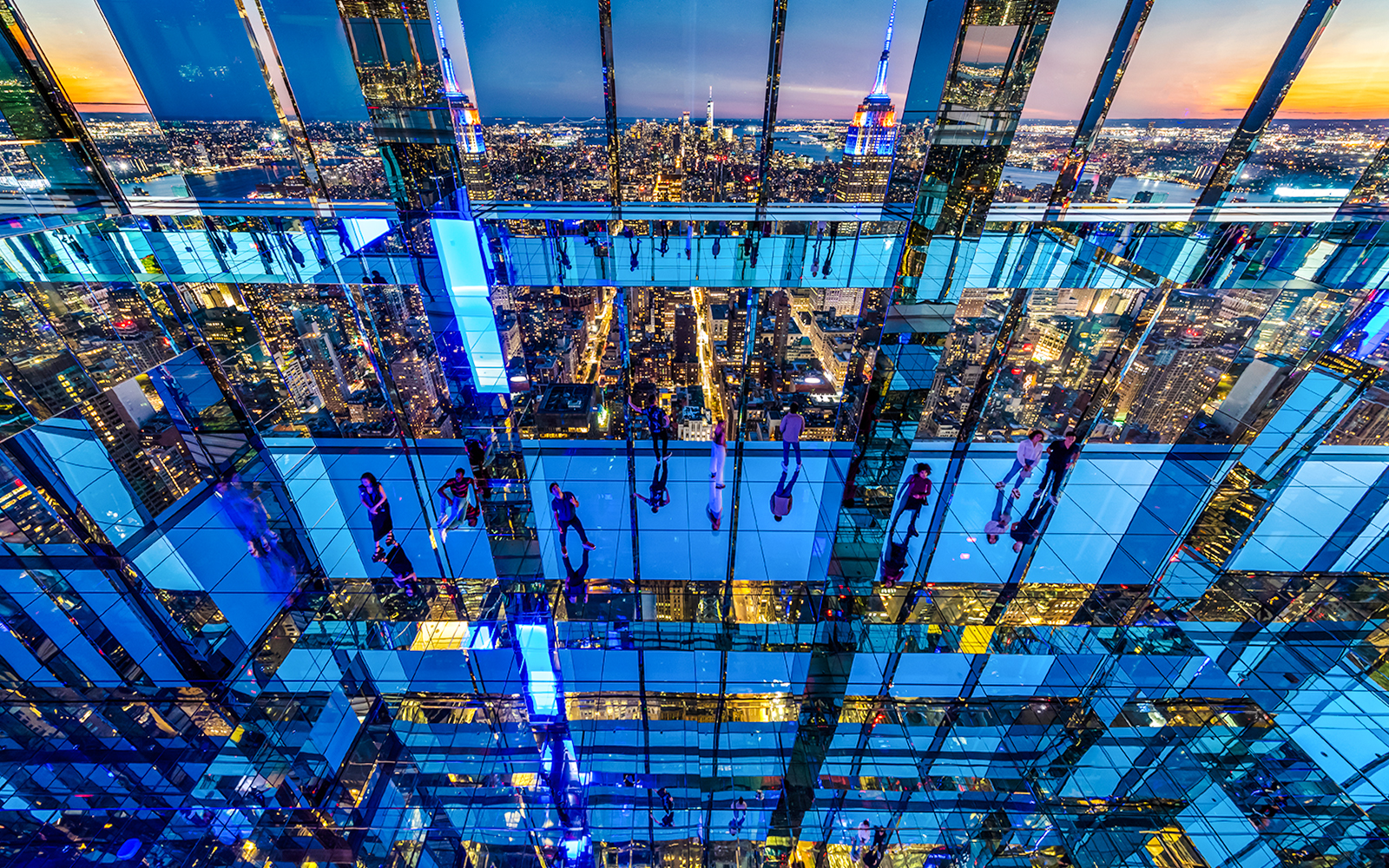 Guests exploring mirrored observation deck at Summit One Vanderbilt, New York City skyline in view.