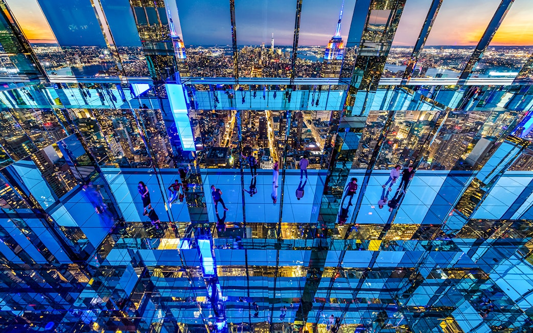 Guests exploring mirrored observation deck at Summit One Vanderbilt, New York City skyline in view.
