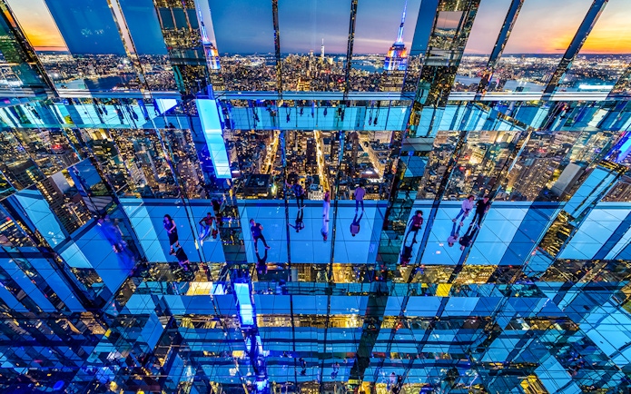 Guests exploring mirrored observation deck at Summit One Vanderbilt, New York City skyline in view.
