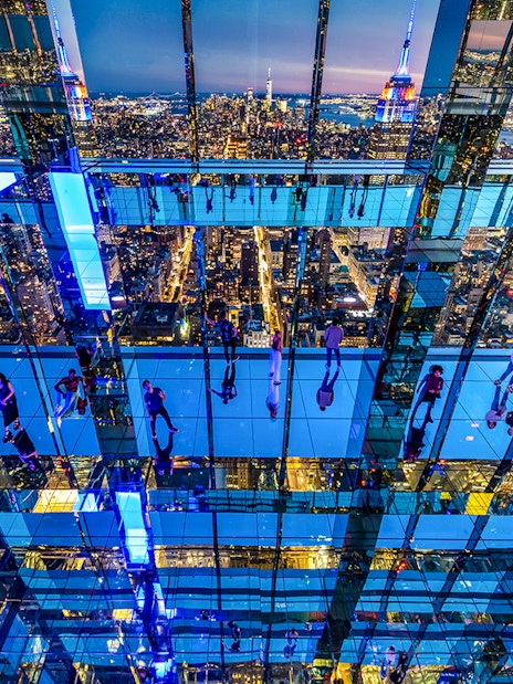 Guests exploring mirrored observation deck at Summit One Vanderbilt, New York City skyline in view.