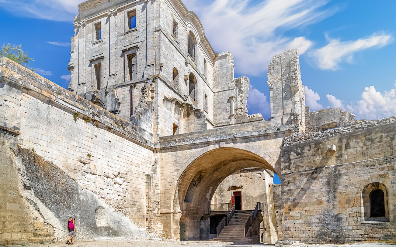 Montmajour Abbey ruins with archway and visitor in Arles, France.