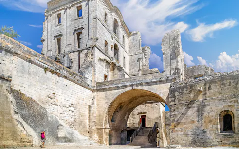Montmajour Abbey ruins with archway and visitor in Arles, France.