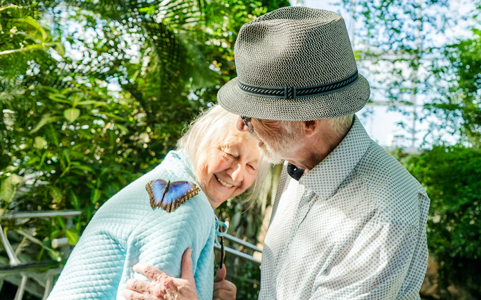 Elderly couple enjoying a butterfly on a shoulder at Niagara Falls Butterfly Conservatory, Canada.