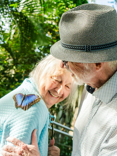 Elderly couple enjoying a butterfly on a shoulder at Niagara Falls Butterfly Conservatory, Canada.