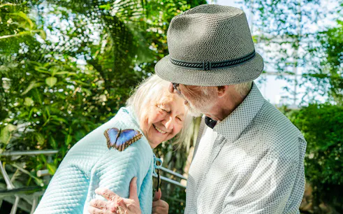 Elderly couple enjoying a butterfly on a shoulder at Niagara Falls Butterfly Conservatory, Canada.