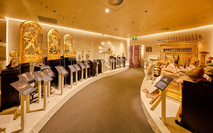 Golden Egyptian artifacts displayed in the Tomb of the Pharaoh exhibit room, Cairns.