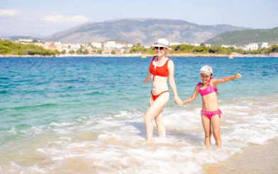 Guests enjoying the beach near Ksamil, Albania, with mountains in the background.