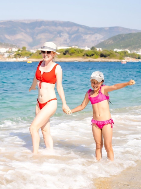 Guests enjoying the beach near Ksamil, Albania, with mountains in the background.