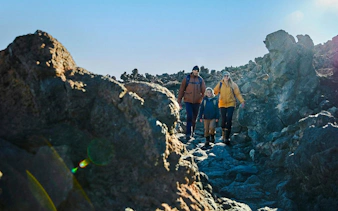 Family hiking on rocky trail at Mount Teide, Tenerife, with cable car tour.