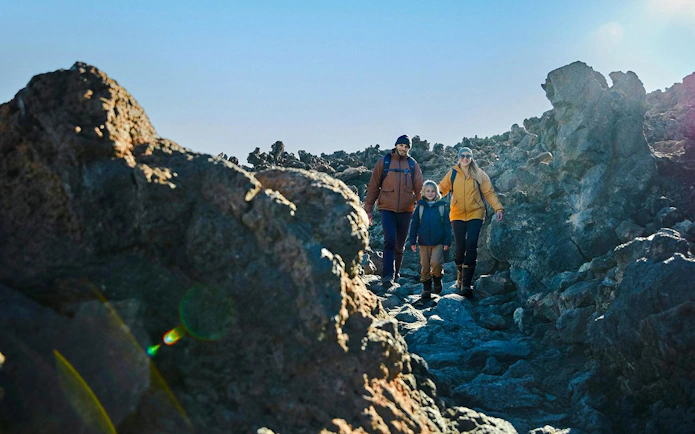 Family hiking on rocky trail at Mount Teide, Tenerife, with cable car tour.