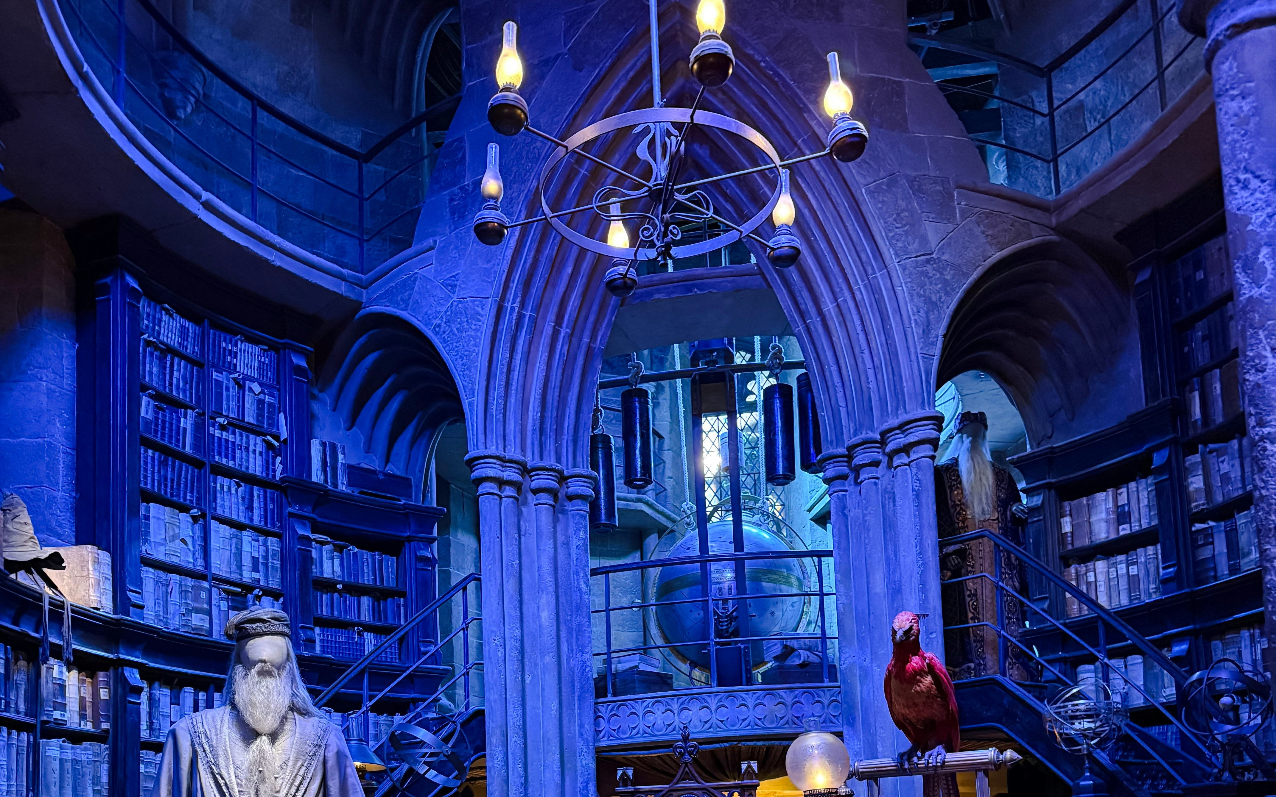Professor Dumbledore’s Office with bookshelves, a chandelier, and a phoenix statue.