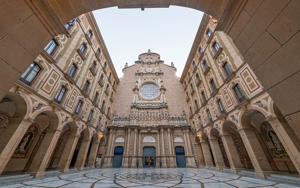 Montserrat Monastery entrance courtyard with ornate facade and archways.