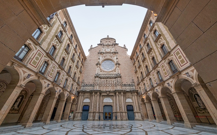 Montserrat Monastery entrance courtyard with ornate facade and archways.