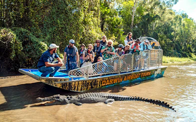 Tourists on a boat observing a crocodile in Finnis River, Top End Safari Camp.