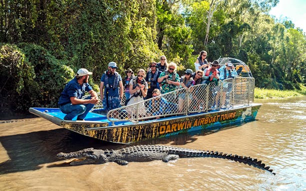 Tourists on a boat observing a crocodile in Finnis River, Top End Safari Camp.