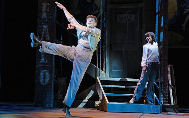 Performer dancing on stage with a partner near a stage door in a theater production of Gypsy.