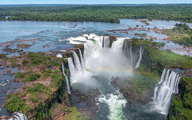 Aerial view of Iguazu Falls from a helicopter ride, showcasing cascading waterfalls and lush rainforest.