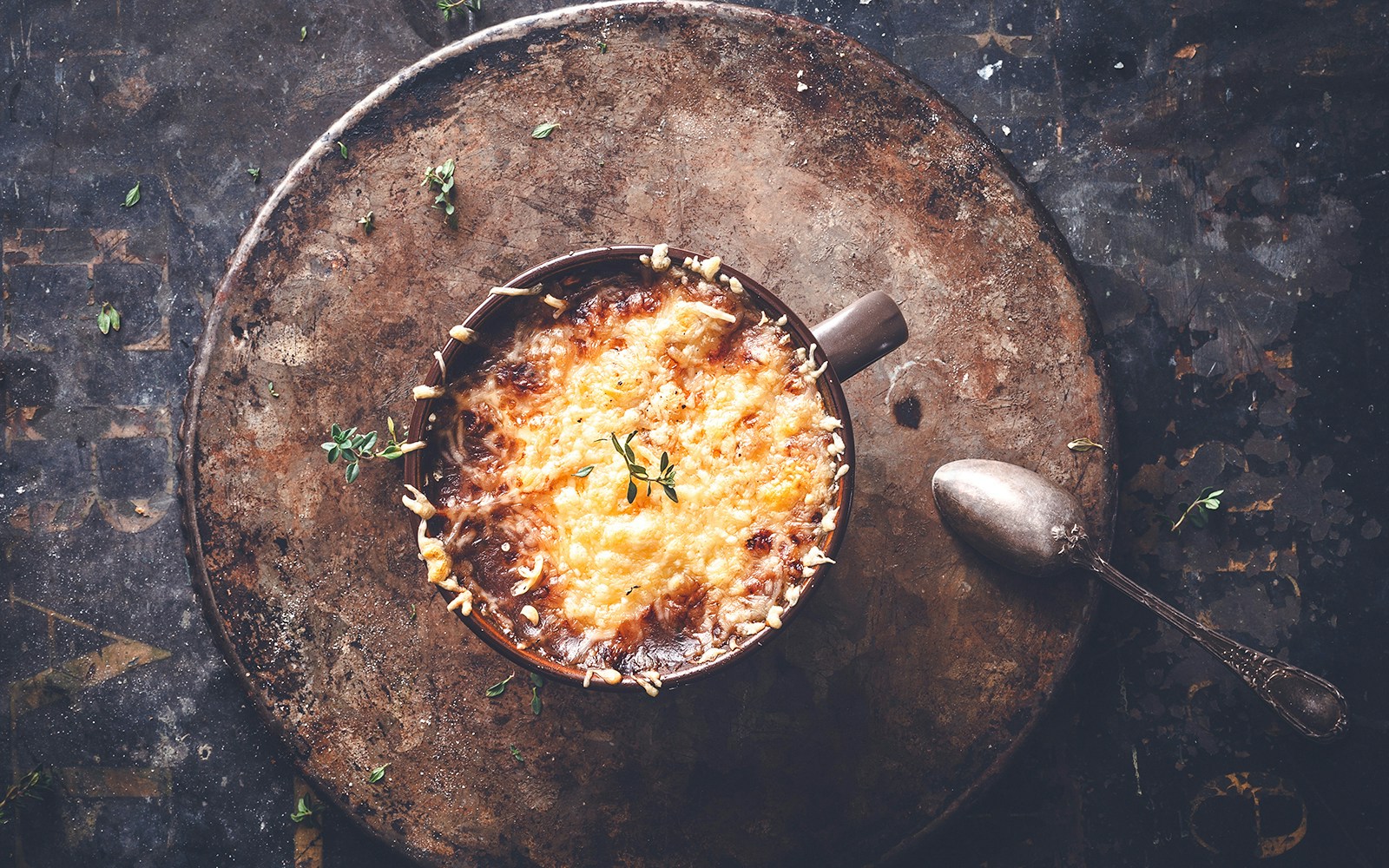 Soupe à l’oignon gratinée in a rustic bowl with herbs, Paris.