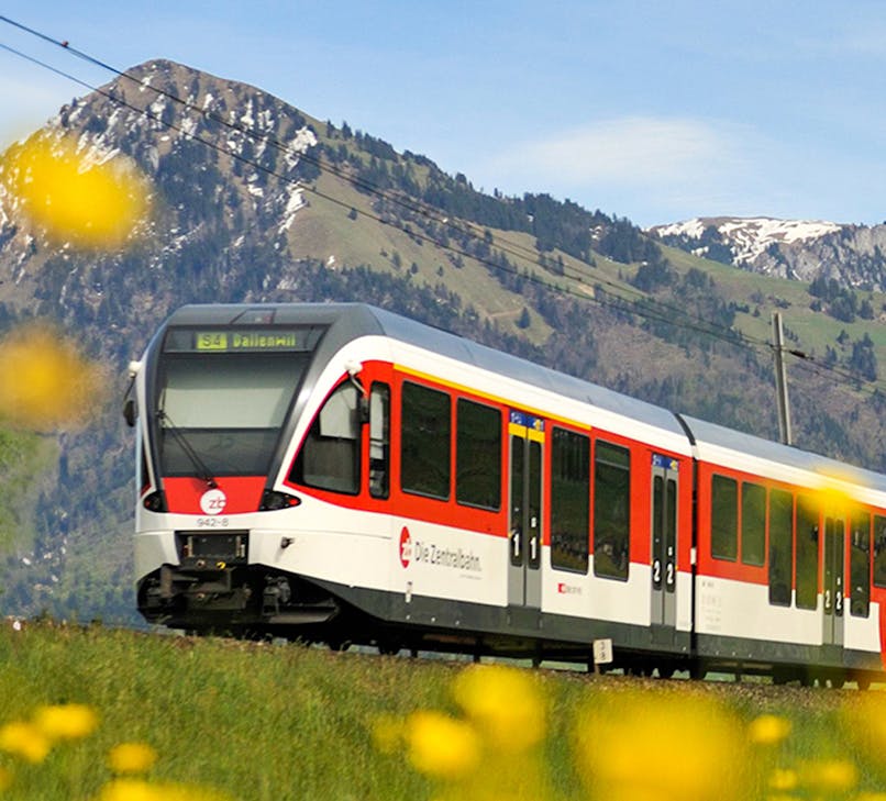 Lucerne–Interlaken Express train traveling through scenic Swiss Alps landscape.