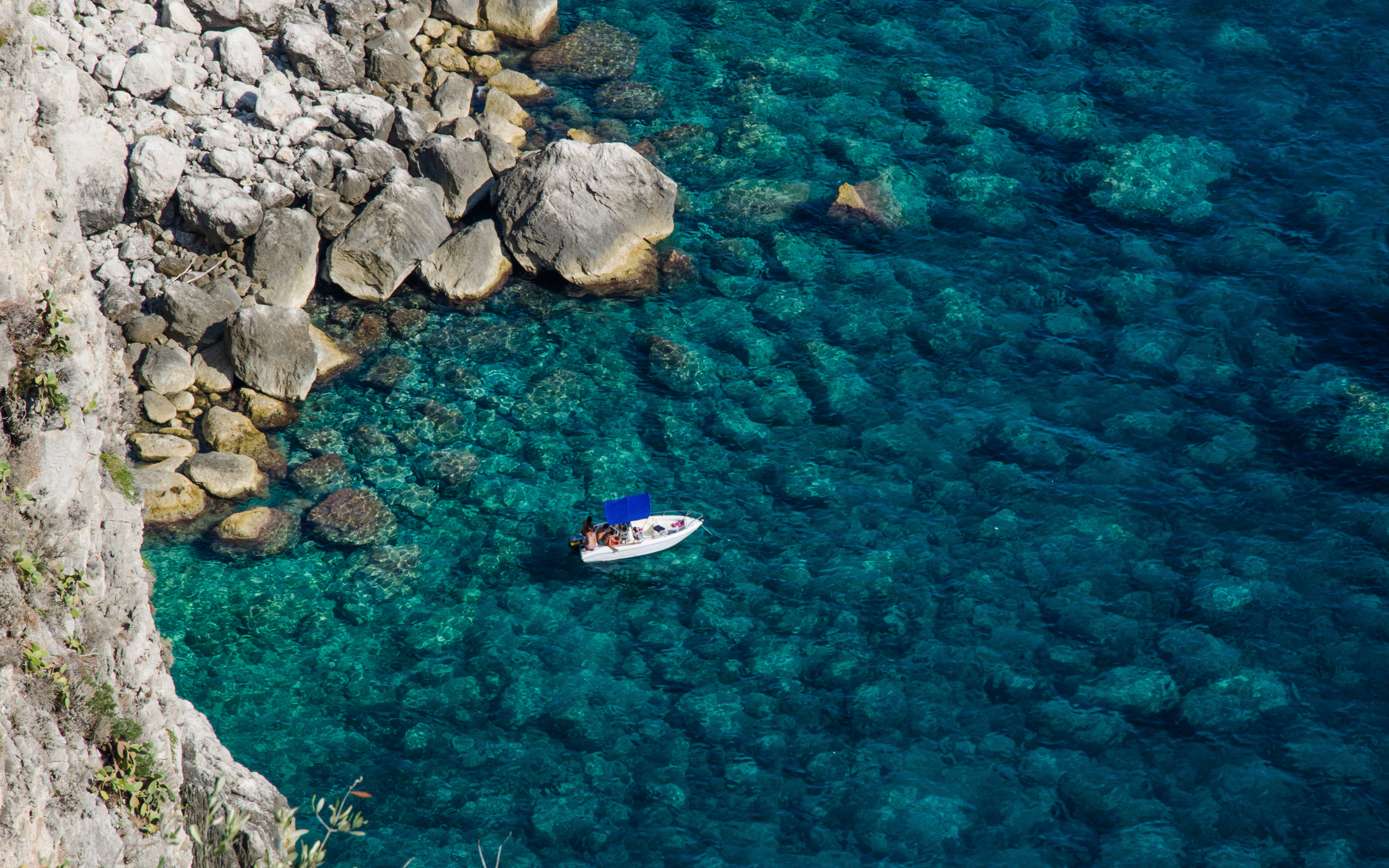 Boat near rocky coastline in Capri, Italy.