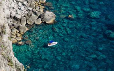 Boat near rocky coastline in Capri, Italy.