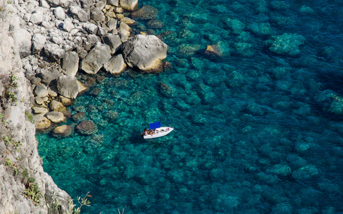 Boat near rocky coastline in Capri, Italy.