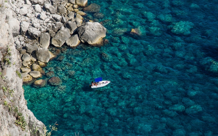 Boat near rocky coastline in Capri, Italy.